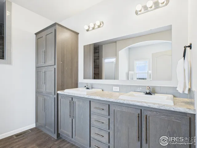a bathroom with a granite countertop double vanity sink and mirror