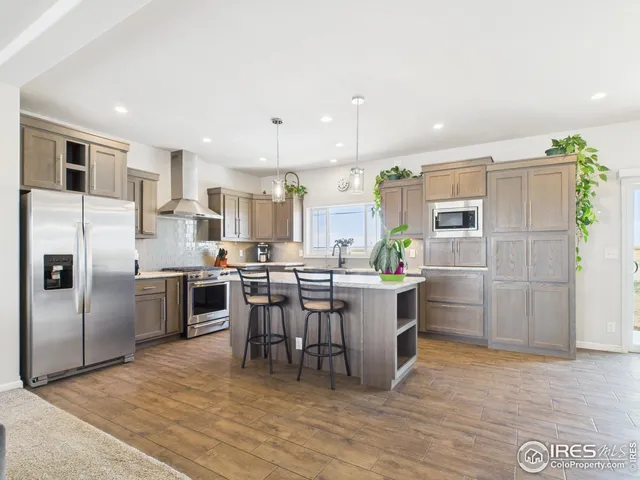 a kitchen with stainless steel appliances a refrigerator a sink a stove a dining table and chairs