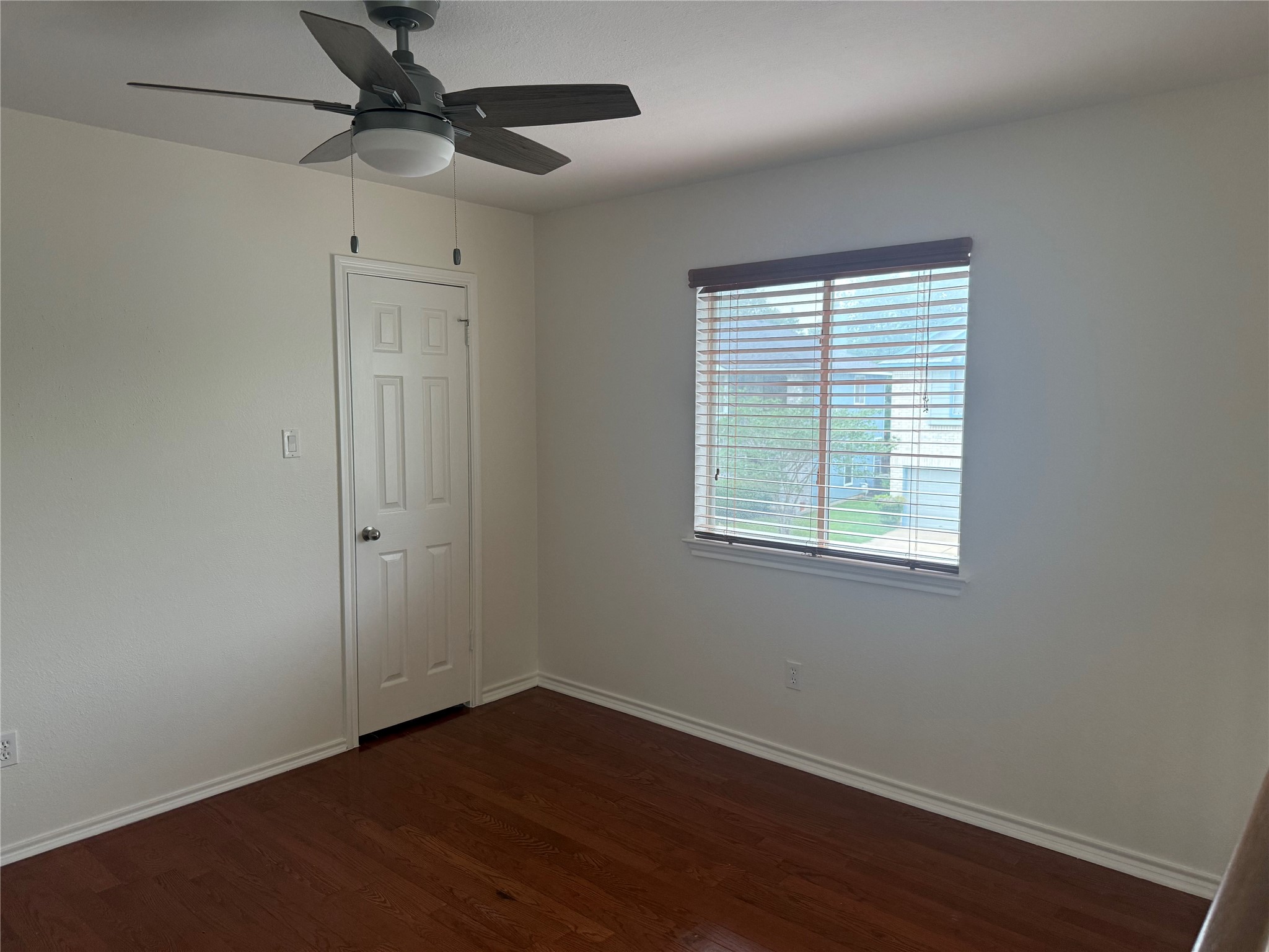 16910 Isle Of Man Road Pflugerville, TX 78660 - Photo 9 of 13 Bright room featuring wood-finish flooring, a white paneled door, and a window with blinds
