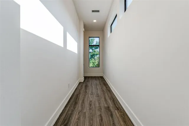 a view of a hallway with wooden floor and a window