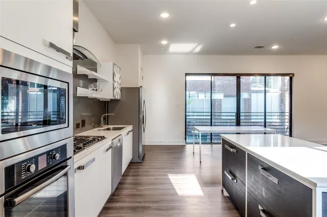 a large kitchen with stainless steel appliances a sink and cabinets