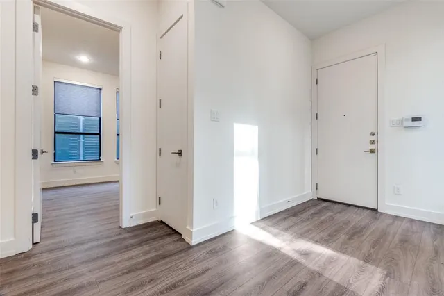 an empty room with wooden floor & windows and bathroom