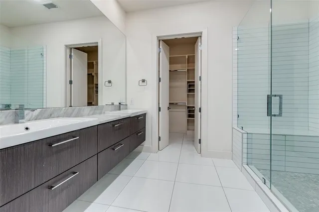 a spacious bathroom with a double vanity sink a mirror and shower