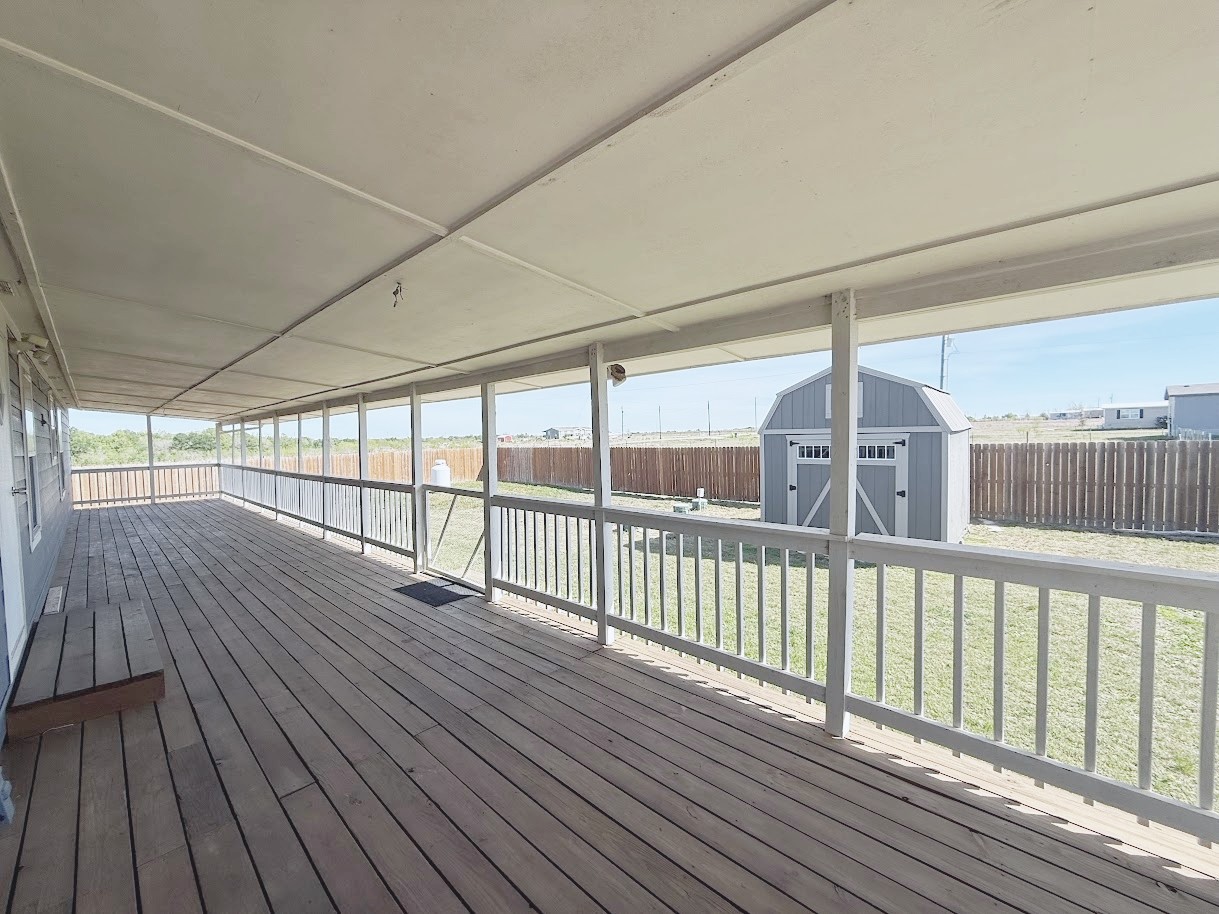 Wooden deck with a storage unit and a fenced backyard