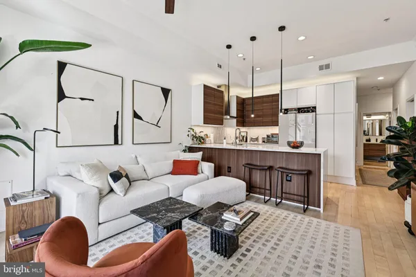 a living room with furniture kitchen view and a wooden floor