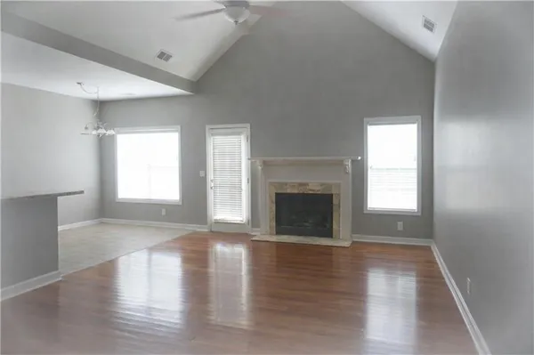an empty room with wooden floor fireplace and windows