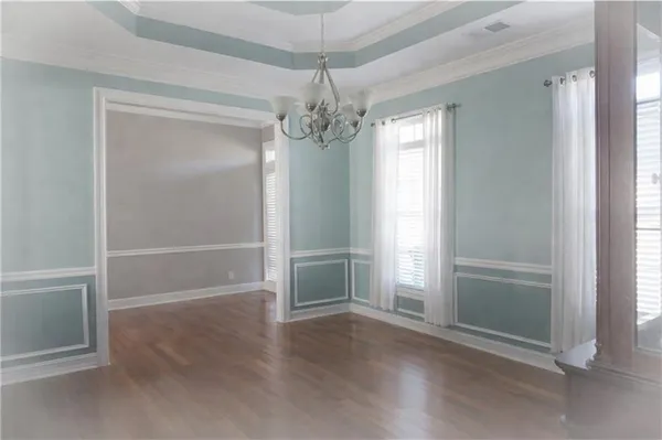an empty room with chandelier fan and windows