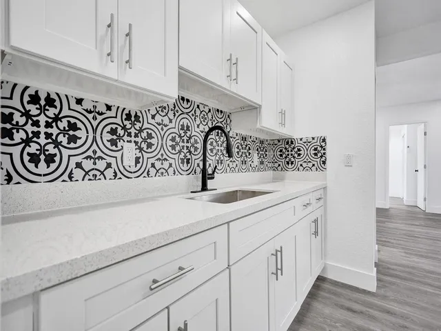 a kitchen with white cabinets and sink
