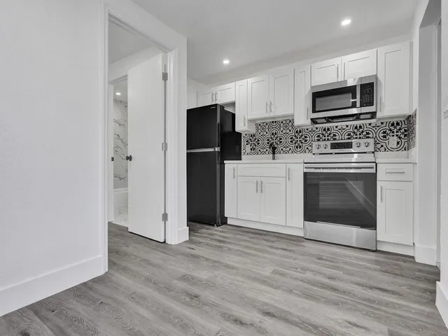 a kitchen with granite countertop a refrigerator and a stove top oven