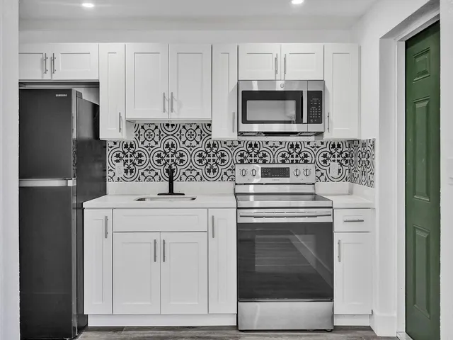 a kitchen with white cabinets and stainless steel appliances