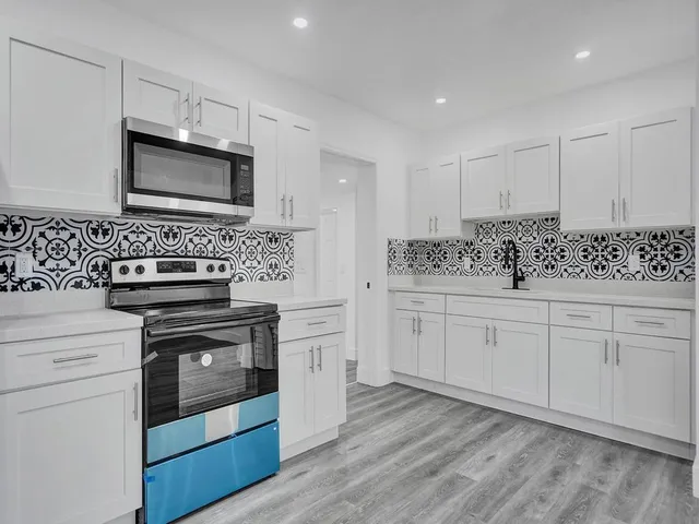 a kitchen with stainless steel appliances granite countertop a stove and white cabinets