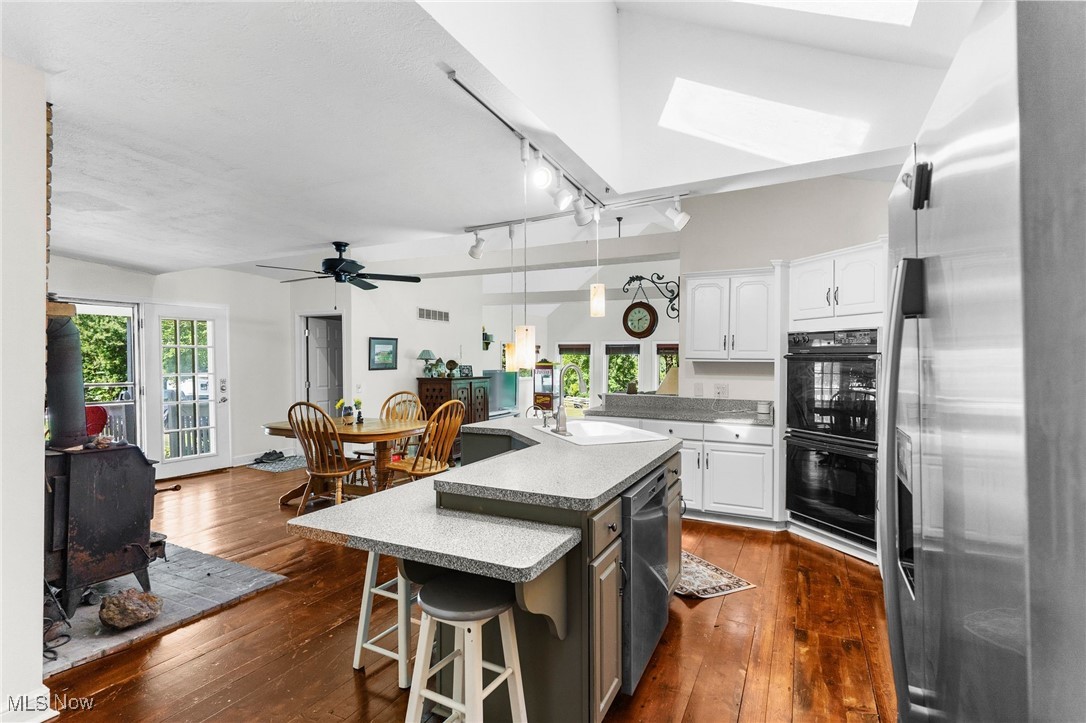 1963 Warner Road Southeast Hubbard, OH 44425 - Photo 5 of 46 Kitchen with white cabinetry, appliances with stainless steel finishes, a kitchen island with sink, a skylight, and sink