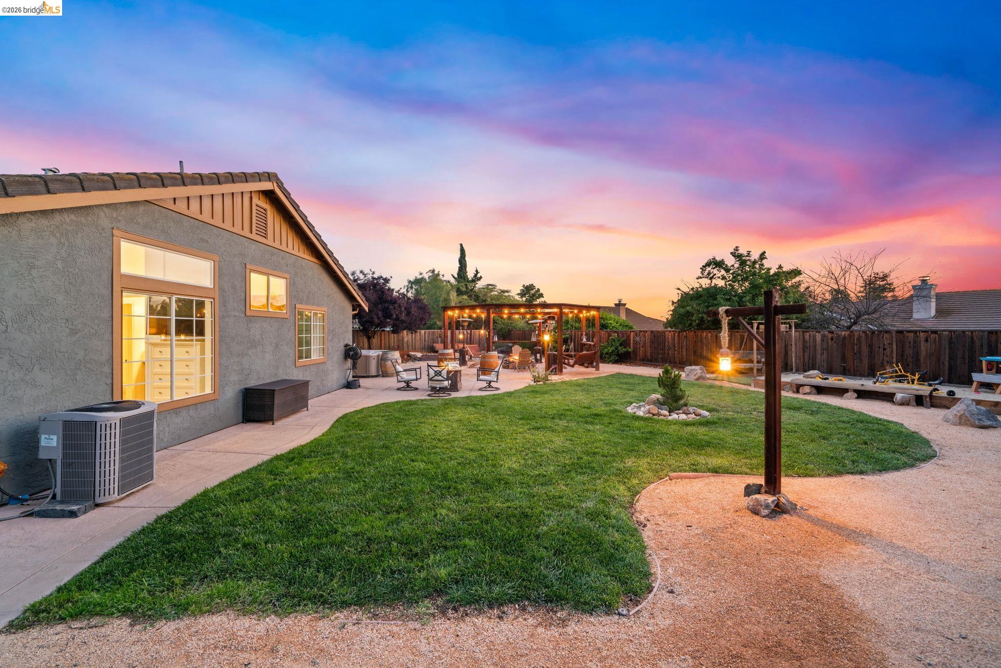 1186 El Rio Court Livermore, CA 94551 - Photo 44 of 60 Spacious backyard featuring a large grass area, a dedicated gravel pathway, and a wood pergola with string lighting