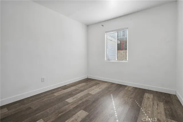 an empty room with wooden floor ceiling fan and windows
