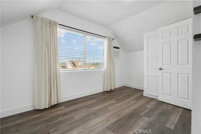 a view of empty room with wooden floor and window
