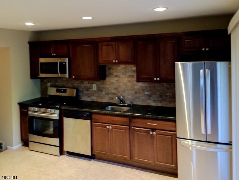 64 Sycamore Court Bernards, NJ 07920 - Photo 7 of 27 a kitchen with stainless steel appliances granite countertop wooden cabinets a stove a microwave and a refrigerator