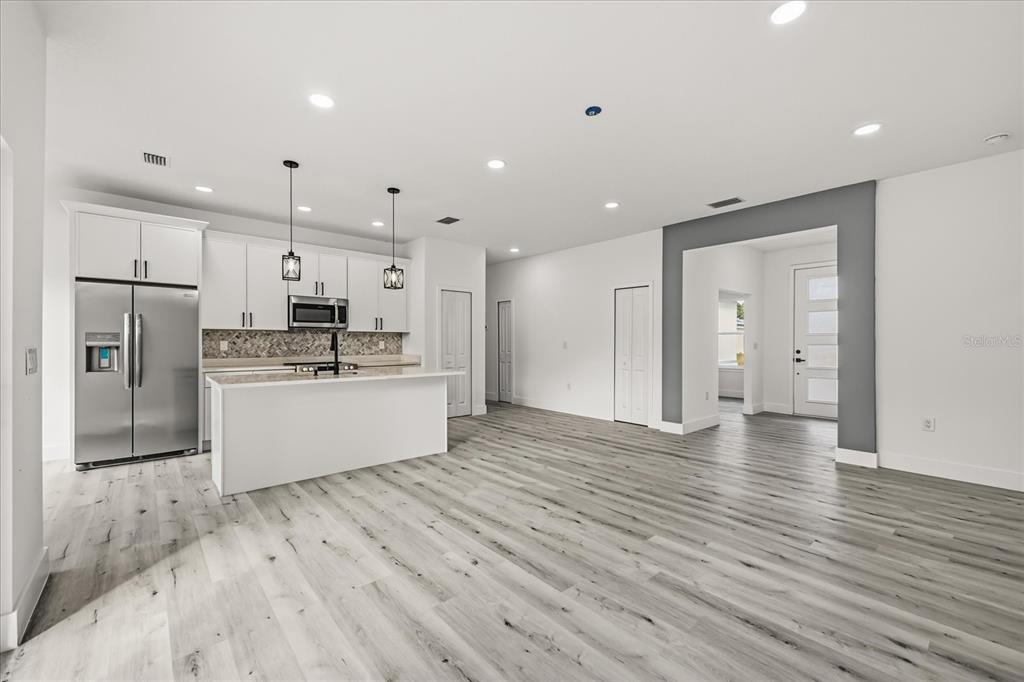 2798 Gainesville Road Southeast Palm Bay, FL 32909 - Photo 10 of 35 a large kitchen with stainless steel appliances kitchen island a stove a refrigerator a sink and white cabinets with wooden floor