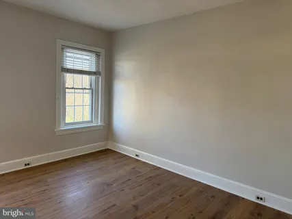 a view of an empty room with wooden floor and closet