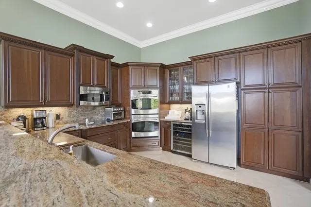 a dining room with stainless steel appliances kitchen island granite countertop a dining table chairs and granite counter tops