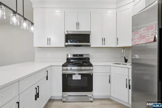 a kitchen with white cabinets stainless steel appliances and sink