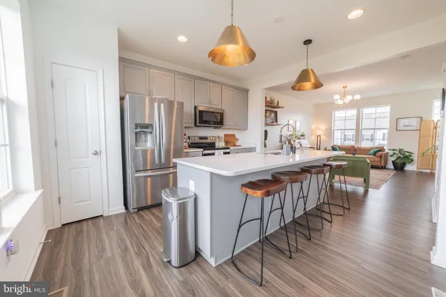 a kitchen with stainless steel appliances a dining table chairs stove and refrigerator