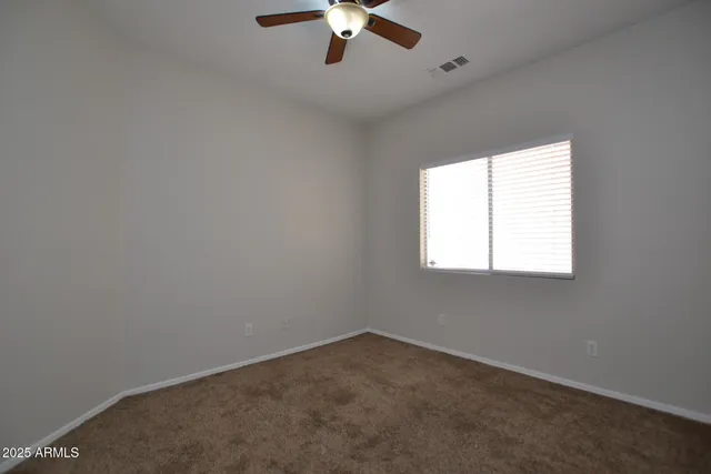an empty room with a window and a fan