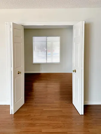 a view of an empty room with wooden floor and a window