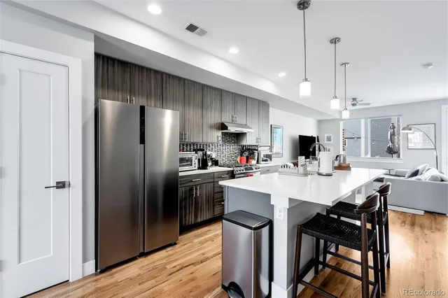 a kitchen with stainless steel appliances a table chairs refrigerator and chairs