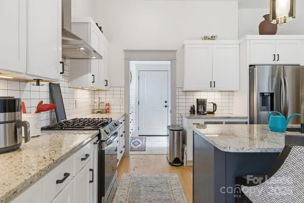 a kitchen with stainless steel appliances kitchen island granite countertop a table chairs and a refrigerator