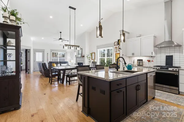 a kitchen with a stove a sink a kitchen island with chairs and cabinets