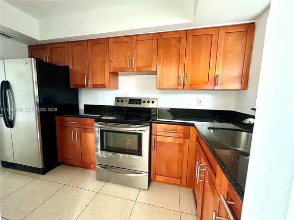 a kitchen with granite countertop a refrigerator stove and sink