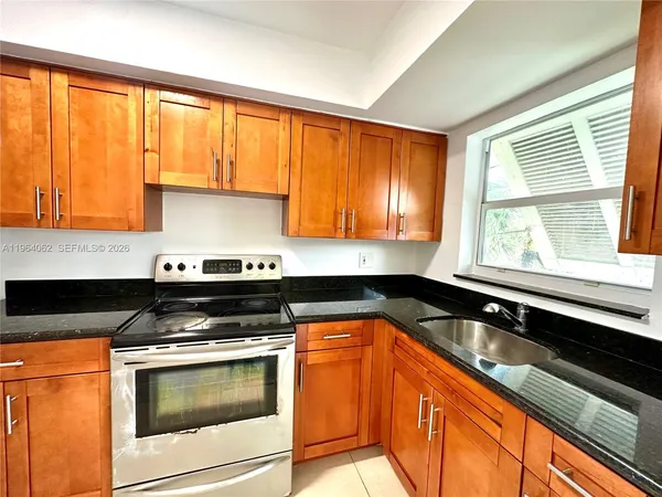 a kitchen with granite countertop stainless steel appliances a sink stove and cabinets