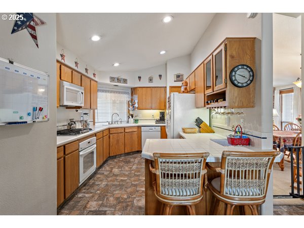 261 Southwest Nancy Circle Gresham, OR 97030 - Photo 8 of 25 a kitchen with stainless steel appliances granite countertop a stove top oven a sink a dining table and chairs