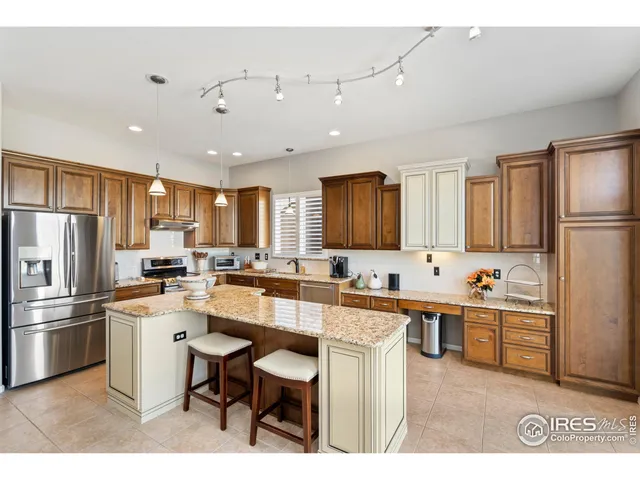 a kitchen with stainless steel appliances a sink a stove a refrigerator cabinets and a dining table