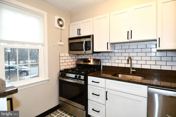 a kitchen with granite countertop a sink stove and refrigerator