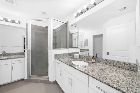a bathroom with a granite countertop double vanity sink and mirror