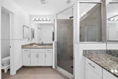 a bathroom with a granite countertop sink a mirror and a shower