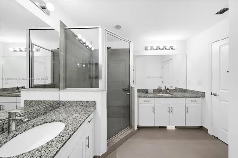 a bathroom with a granite countertop double vanity sink and a mirror