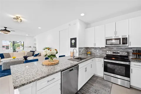 a kitchen with granite countertop white cabinets and white appliances