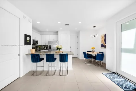 a kitchen with stainless steel appliances kitchen island granite countertop a refrigerator and a dining table