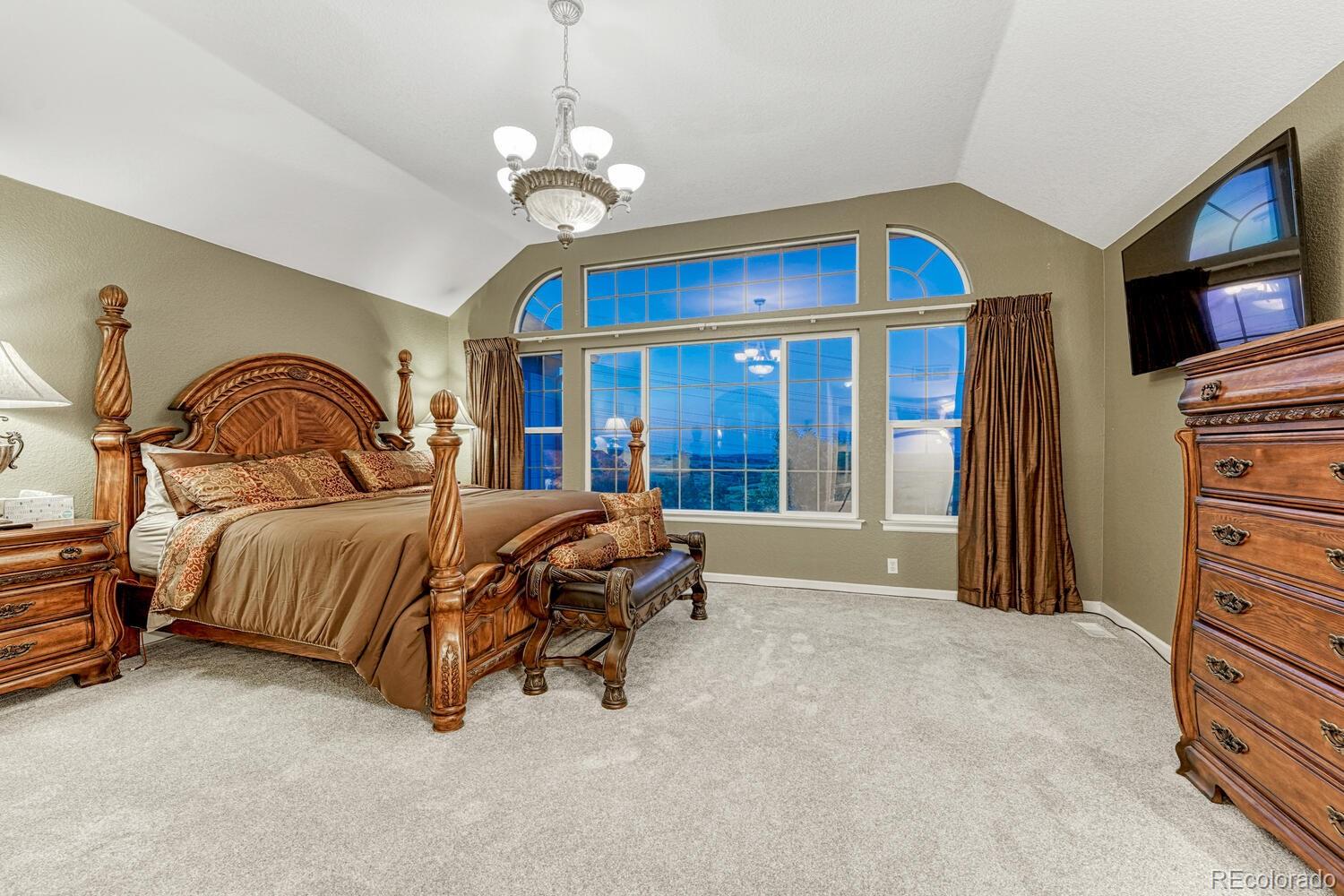 12350 Turquoise Terrace Street Castle Pines, CO 80108 - Photo 19 of 50 a bedroom with a bed and a chandelier