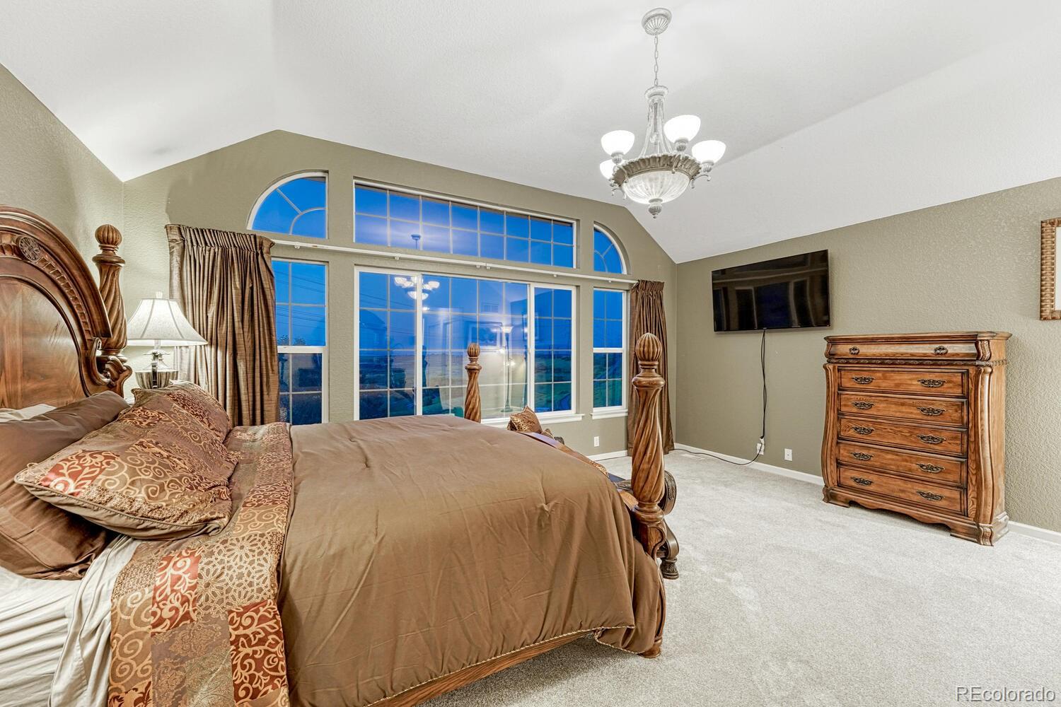 12350 Turquoise Terrace Street Castle Pines, CO 80108 - Photo 21 of 50 a bedroom with a bed and a chandelier