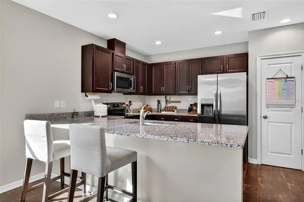 a kitchen with stainless steel appliances granite countertop a refrigerator a stove a sink a dining table and chairs