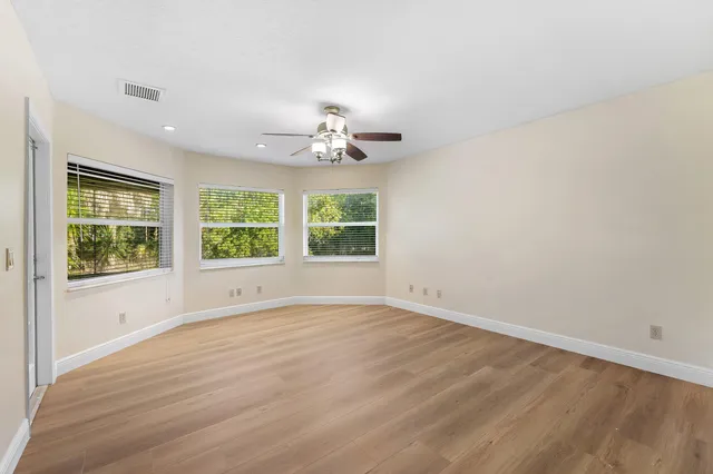 a view of an empty room with a window and wooden floor