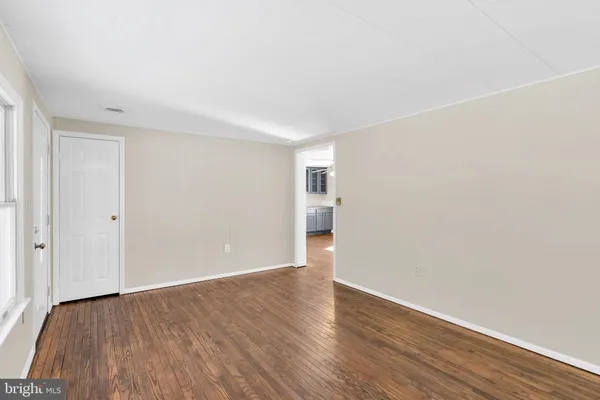 a view of an empty room with wooden floor and closet