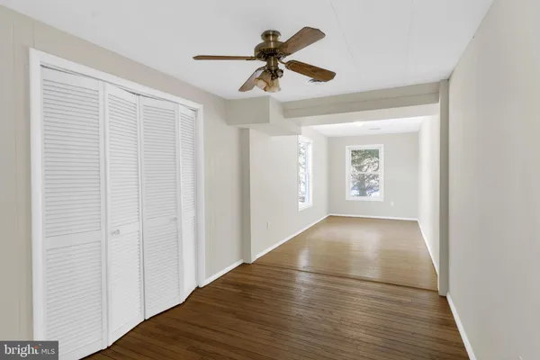 a view of empty room with wooden floor and ceiling fan