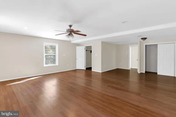 a view of an empty room with window and wooden floor