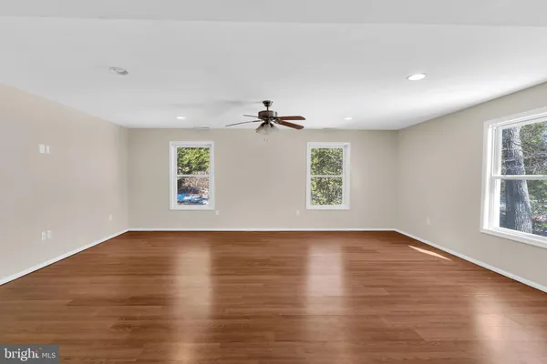 an empty room with wooden floor chandelier and windows