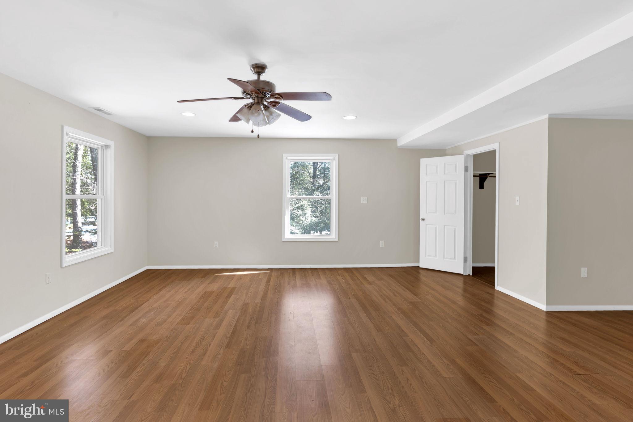 1150 Calvert Beach Road St. Leonard, MD 20685 - Photo 19 of 42 an empty room with wooden floor chandelier fan and windows