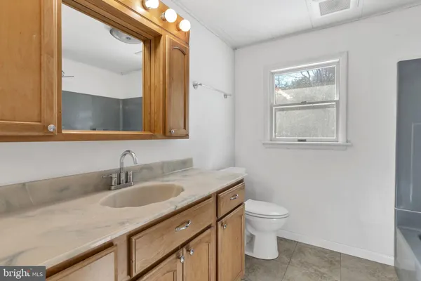 a bathroom with a granite countertop sink a toilet and a mirror